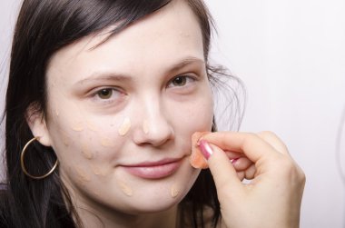 Makeup artist deals Foundation on the model's face clipart