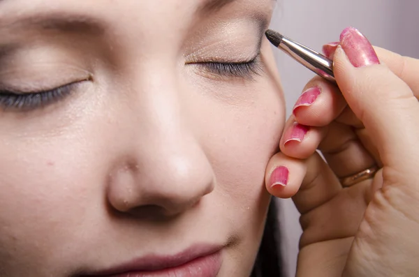 Maquilleur dans le processus de couleurs de maquillage modèle paupières supérieures — Photo