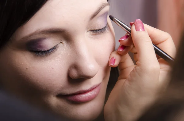 Maquiagem artista no processo de maquiagem cores superior pálpebras modelo — Fotografia de Stock