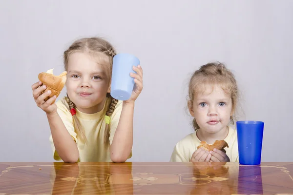 Duas crianças comem um queque na mesa — Fotografia de Stock