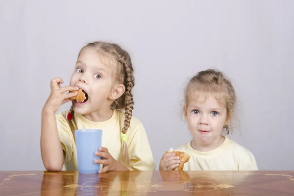 Duas crianças comem um queque na mesa — Fotografia de Stock