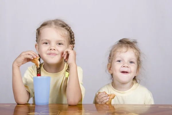 Två barn äter en muffin vid bordet — Stockfoto