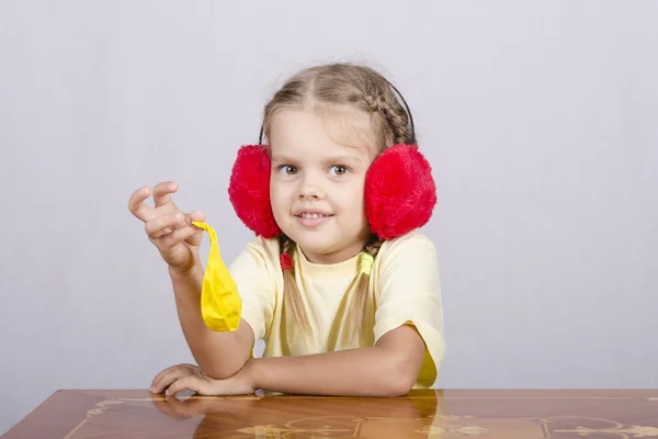 Girl with headphones and a ball is sitting at table — Stock Photo, Image