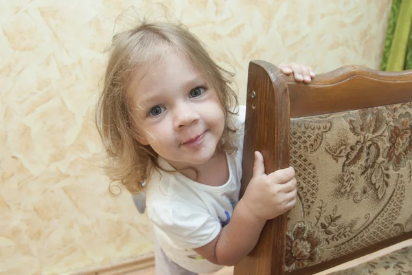 Girl peeks out from behind the chair — Stock Photo, Image