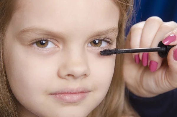 Make-up artiest schildert wimpers op van het meisje gezicht — Stockfoto