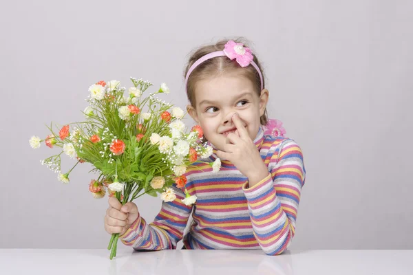 Girl with a bouquet of flowers sitting at table — Stock Photo, Image