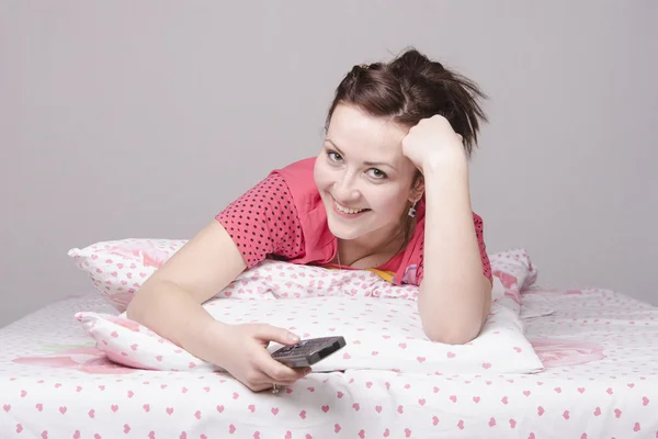 Mädchen im Bett lacht, während sie fernsieht — Stockfoto