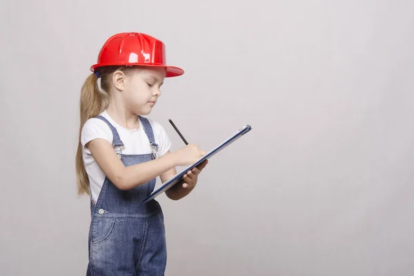 Child stands helmet and writes in the folder — Stock Photo, Image