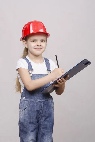 Child five years worth helmet and writes in folder — Stock Photo, Image