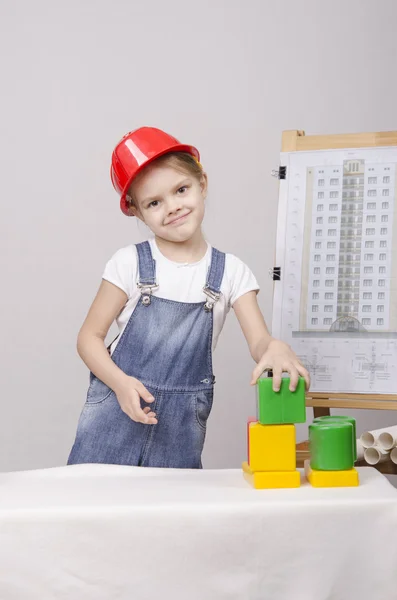 Meisje bouwer in helm bouwt een huis op tekening — Stockfoto