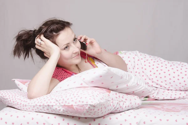 Young girl talking on phone lying in bed — Stock Photo, Image