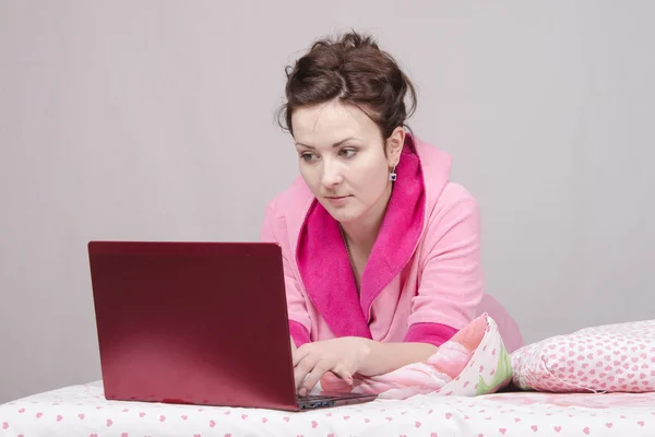 Girl in bed concentrated works for laptop — Stock Photo, Image
