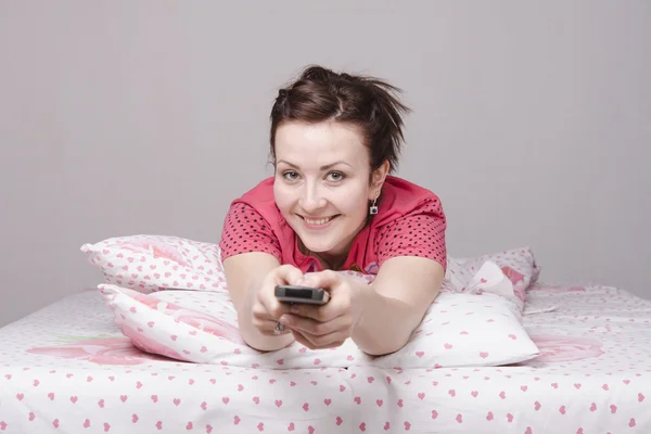 Chica joven está viendo la televisión en la cama — Foto de Stock