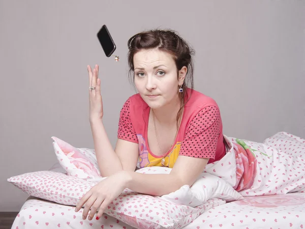 Jong meisje in het bed en gooide telefoon — Stockfoto