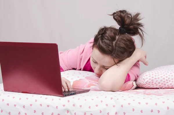 Mädchen schläft im Bett für einen Laptop — Stockfoto