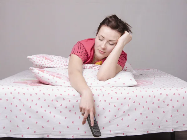 Ung tjej somnade med fjärrkontroll i sängen — Stockfoto