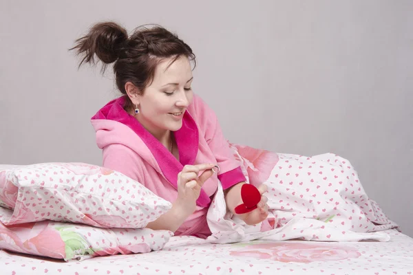 Ragazza a letto considera un anello regalo — Foto Stock