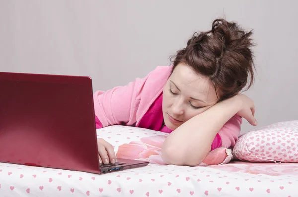 Mädchen schläft im Bett für einen Laptop — Stockfoto