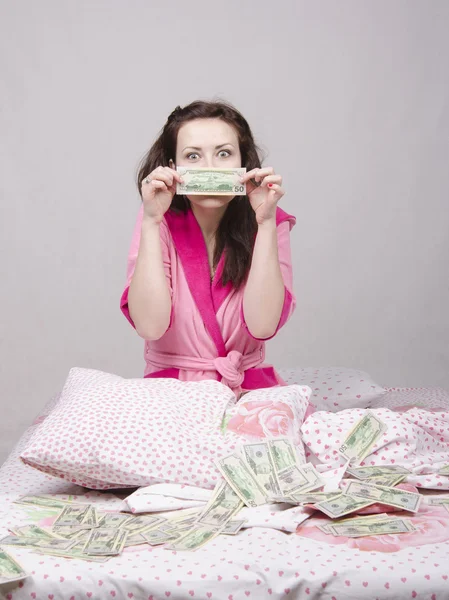 Yatağın üzerine oturan kız para sevinir — Stok fotoğraf