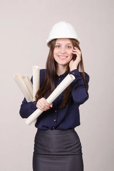 Meisje een helm praten over telefoon met blueprints in de hand — Stockfoto