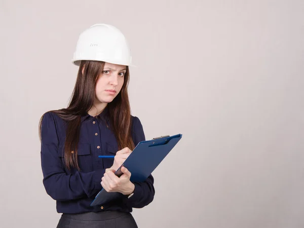 Doordachte meisje een helm schrijft in potlood map — Stockfoto