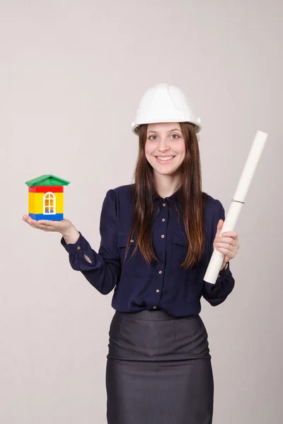 Meisje staat met een huis bouwer en tekening in handen — Stockfoto