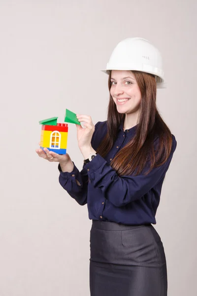 Bouwvakker staat met een huis in de handen van — Stockfoto