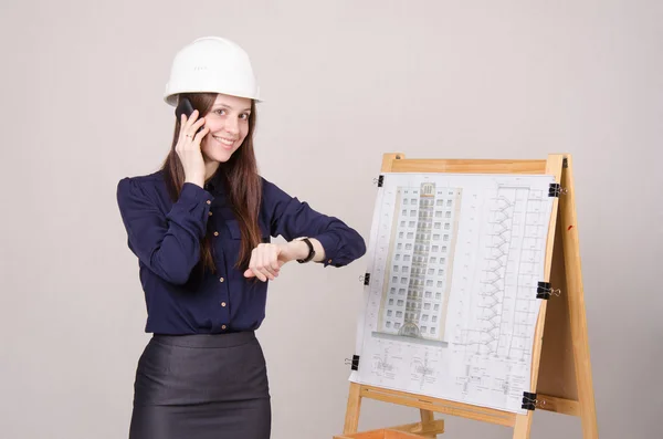 Architect meisje praten over telefoon en kijken naar zijn horloge — Stockfoto