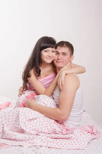 Newlyweds embracing sitting in bed — Stock Photo, Image