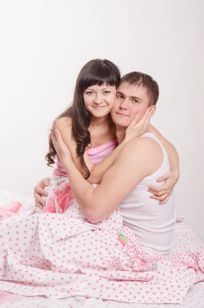 Young beautiful girl embraces the guy in bed — Stock Photo, Image