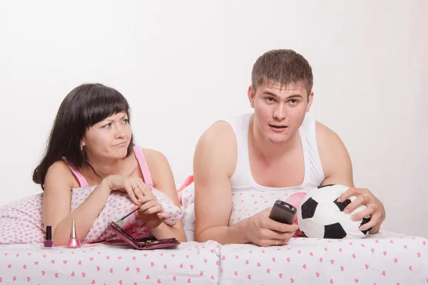 Skeptical wife looking at her husband football fan — Stock Photo, Image