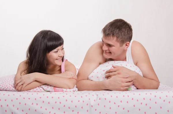 Homem e mulher sorrindo um para o outro na cama — Fotografia de Stock