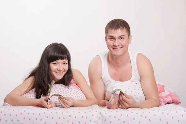Girl and guy with a wad of money in bed — Stock Photo, Image