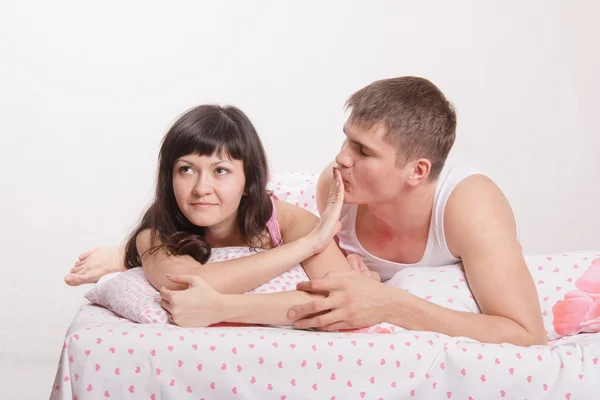 genç kız yatakta bir adamı öpmek için reddediyor.