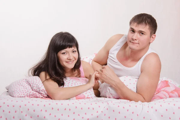 Young girl and the guy put up, lying in bed — Stock Photo, Image