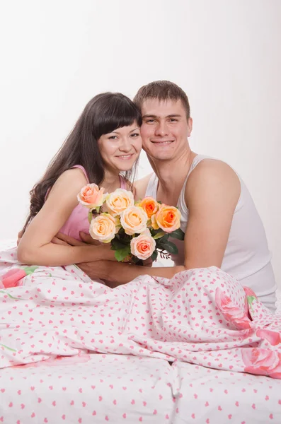 Feliz joven hermosa pareja sentada en la cama —  Fotos de Stock