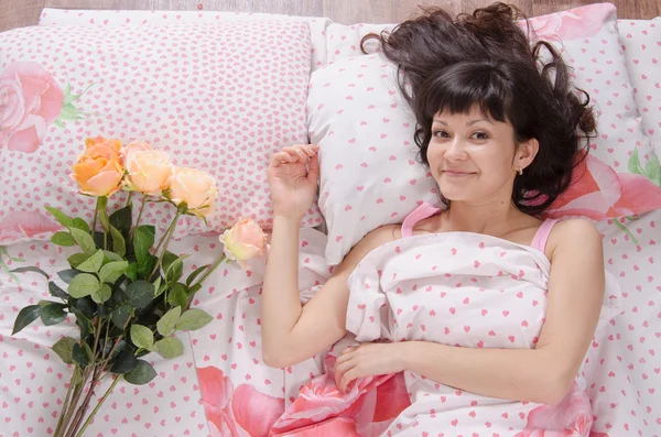 Leuk meisje in bed verrast geschonken een boeket rozen — Stockfoto