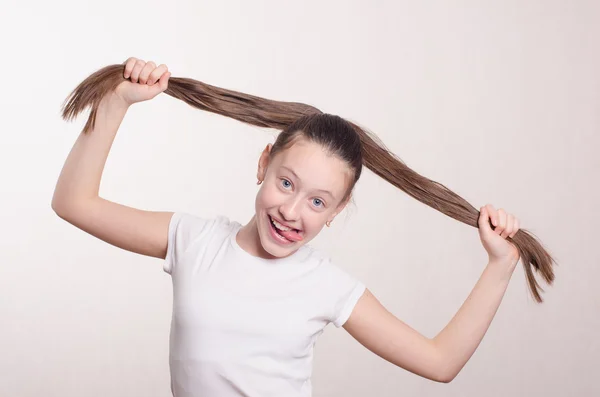 Двенадцатилетняя девочка держит волосы и язык за зубами — стоковое фото