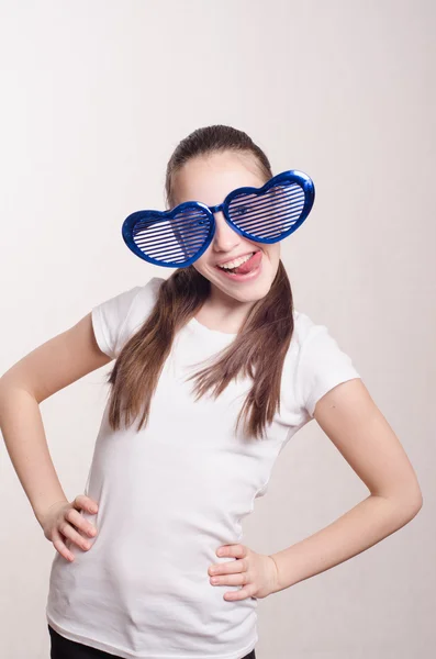 Смешная маленькая девочка в больших очках показывает язык — стоковое фото