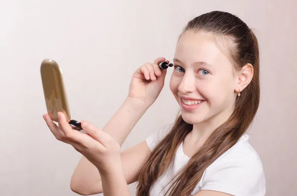 Twelve year old girl paints eyelashes mascara — Stock Photo, Image