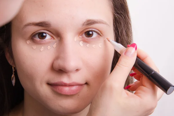 Makeup artist applies foundation on eyelids of young girl — Stock Photo, Image