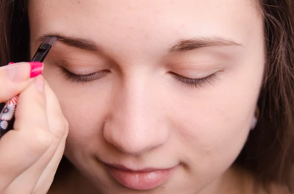 Maquiagem artista escova sobrancelhas traz jovem menina — Fotografia de Stock
