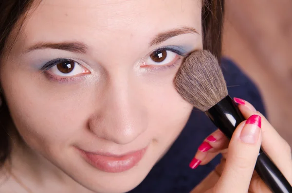 Makeup artist applies powder on face of beautiful girl — Stock Photo, Image