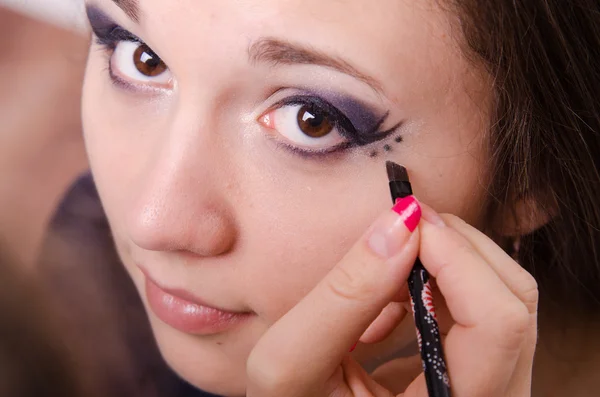 Maquillaje artista pinta un punto sobre las flechas en los ojos de la chica —  Fotos de Stock