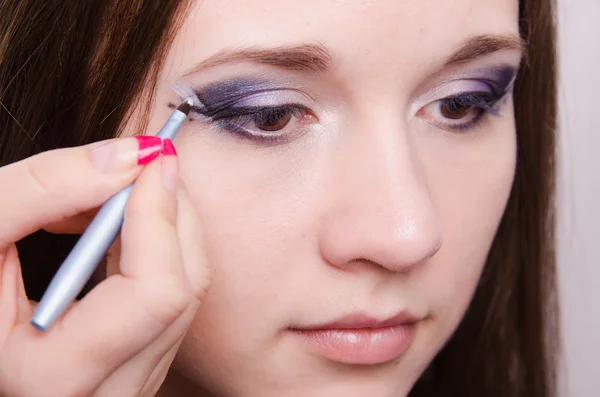 Trauriges Mädchen Make-up Artist zeichnet Pfeile — Stockfoto