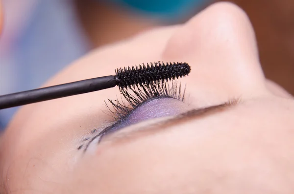 Makeup artist målar ögonfransarna flicka — Stockfoto