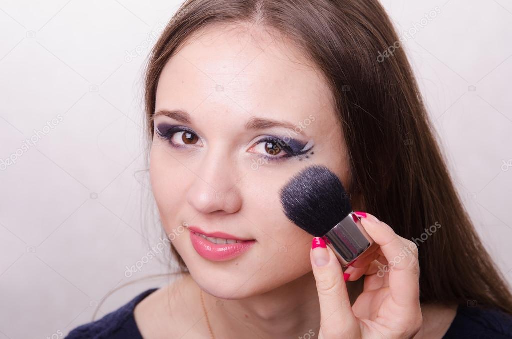 Makeup artist brush powders face of a beautiful girl
