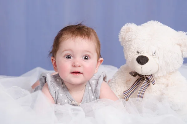 Six-month baby girl with teddy bear lying on couch — Stock Photo, Image