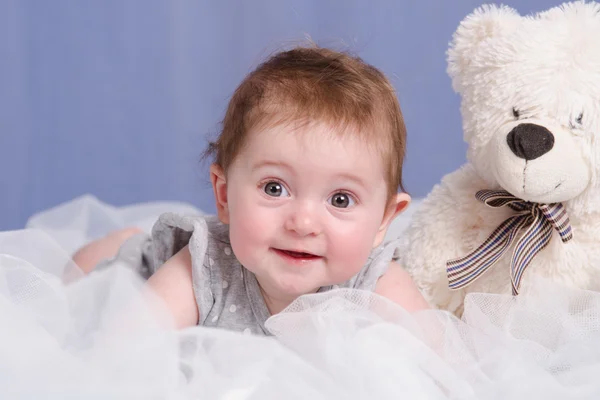Six-month baby girl with teddy bear on sofa — Stock Photo, Image