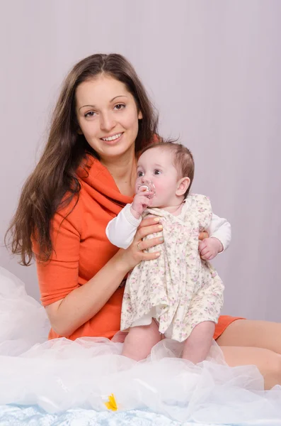 Moeder en dochter op het bed zes maanden durende — Stockfoto